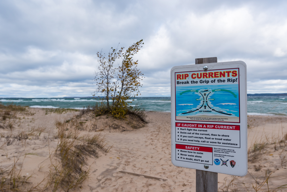 Summer Vacation Safety Tips.
Sign warning of dangerous rip currents on Lake Michigan Beach, Michigan, USA.