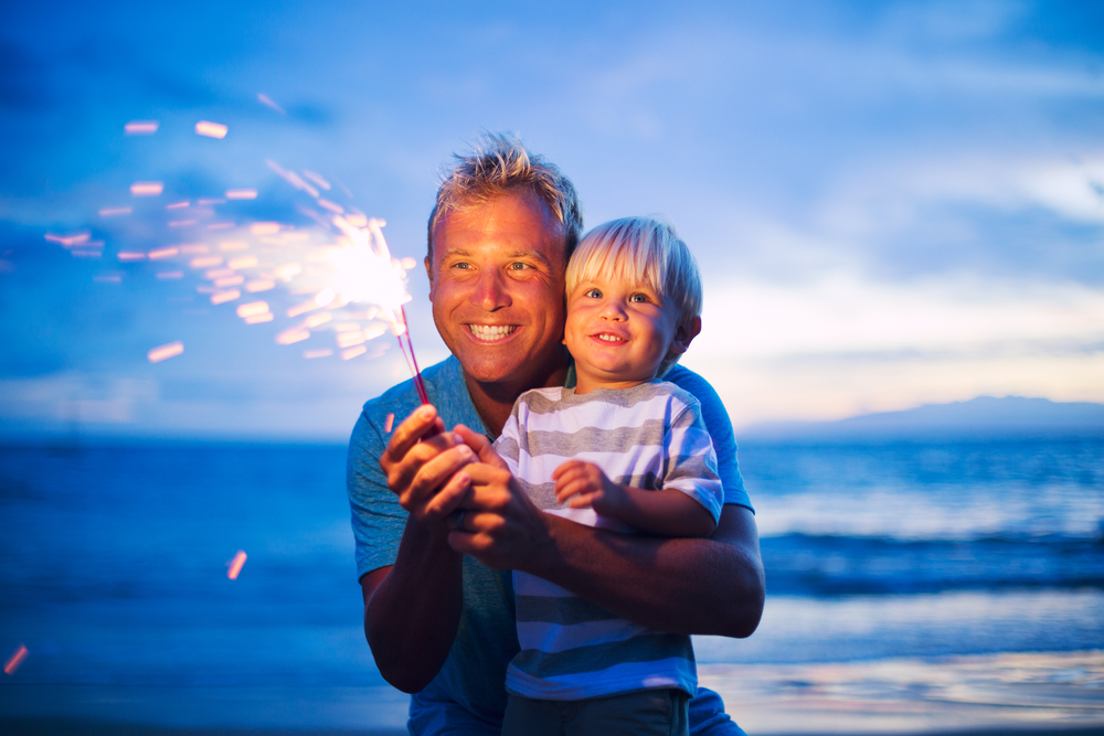 Summer Vacation Safety Tips.
Father and son lighting sparklers on the beach at sunset