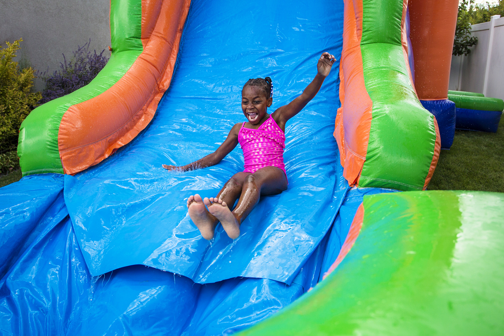 Summer staycation ideas.
Happy girl sliding down a waterslide