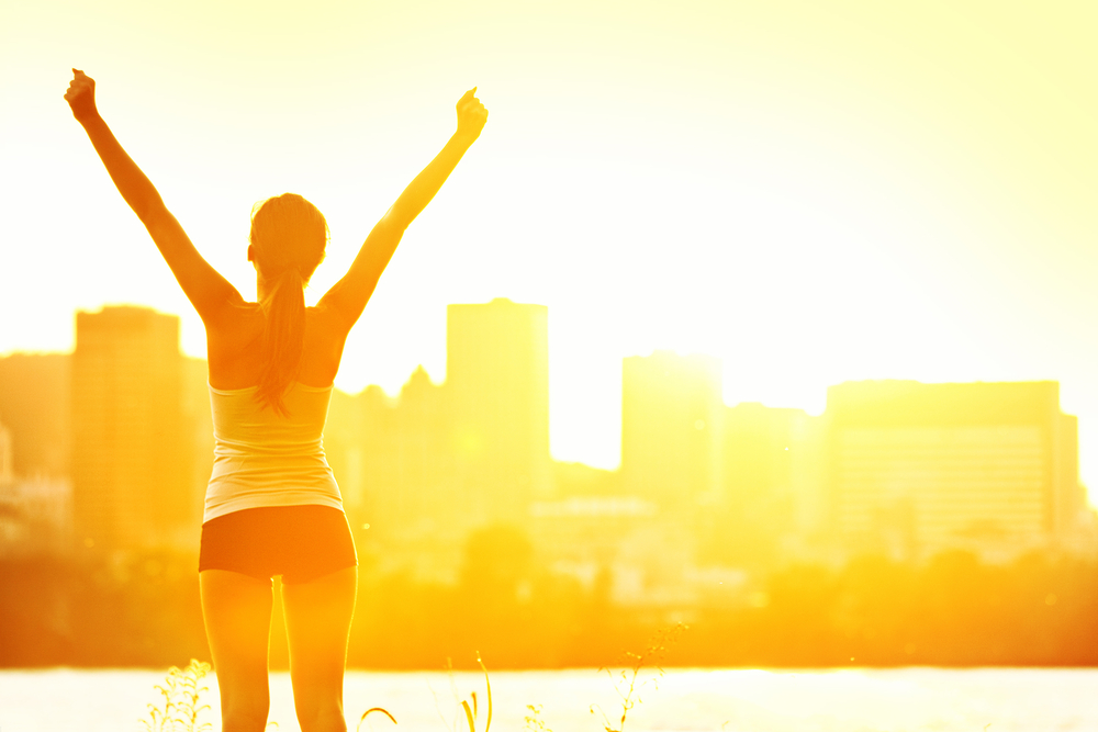 Running While Traveling.
Success winner woman standing with arms up joyful after outdoors workout. Half silhouette on sunny warm summer day with city skyline in background, From Montreal, Quebec, Canada.