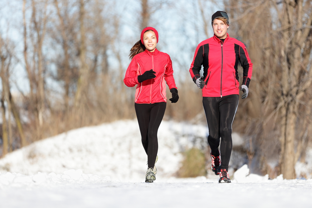 Running While Traveling.
Sport couple running in winter. Runners jogging in snow in city park. 
