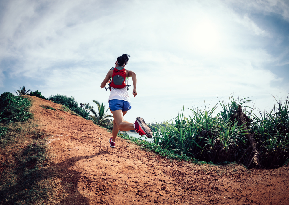 Running While Traveling.
Woman trail runner running on seaside hills.