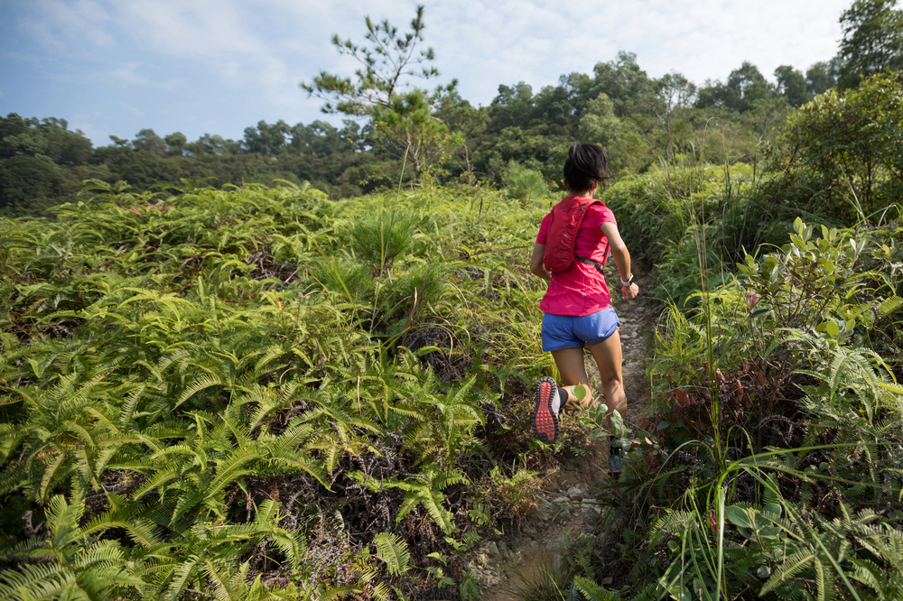 Running While Traveling.
Woman trail runner running up on mountain slope in tropical forest.
