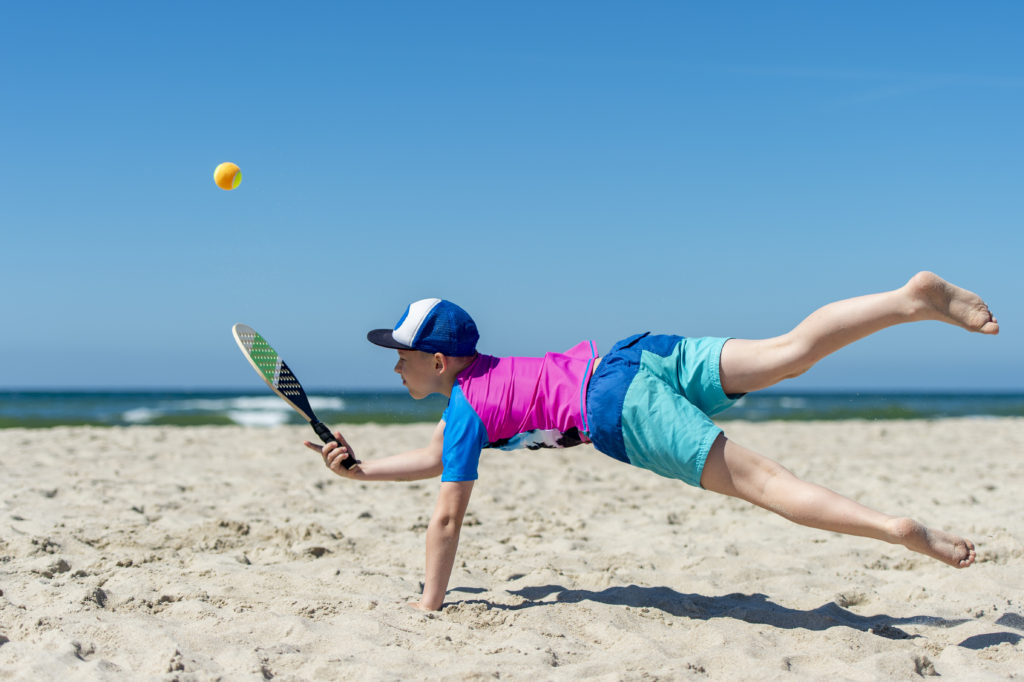 Gifts for Beach Lovers.
Young boy playing tennis on beach. Summer sport concept