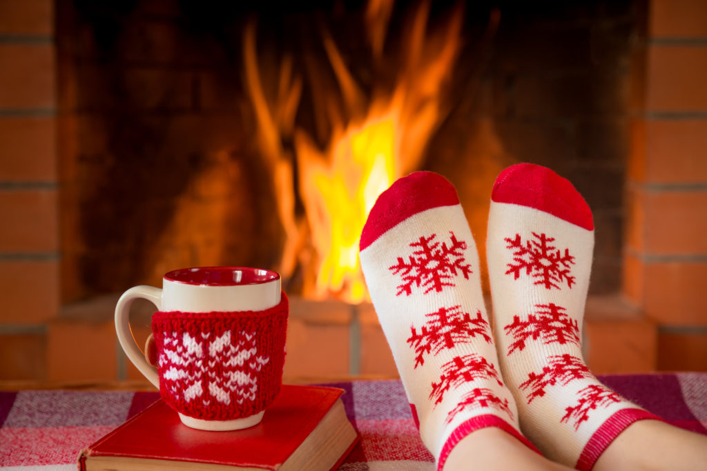 Christmas Bucket List Ideas.
Woman in Christmas socks near fireplace. Person relaxing at home. Winter holiday Xmas and New Year concept
