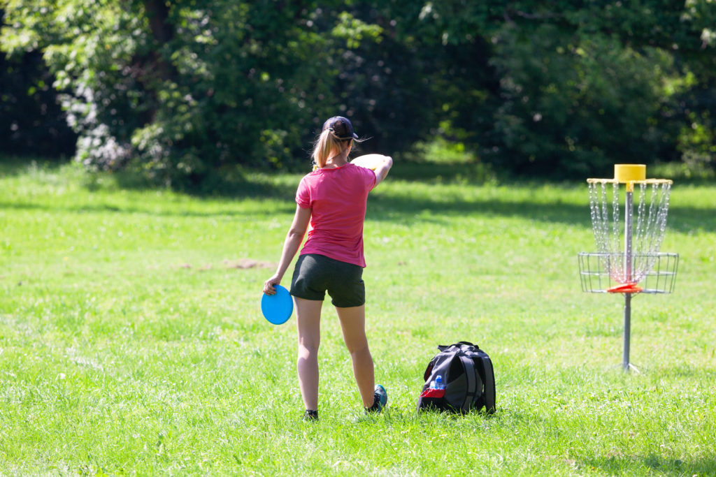 Outdoor Activities Gainesville FL.
Young woman playing flying disc sport game in the park