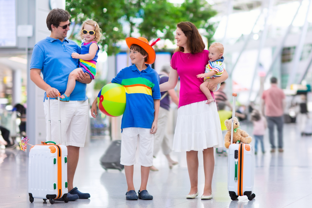 Family Travel Tips.  Family traveling with kids. Parents with children at international airport with luggage. Mother and father hold baby, toddler girl and boy flying by airplane. Travel with child for summer vacation.