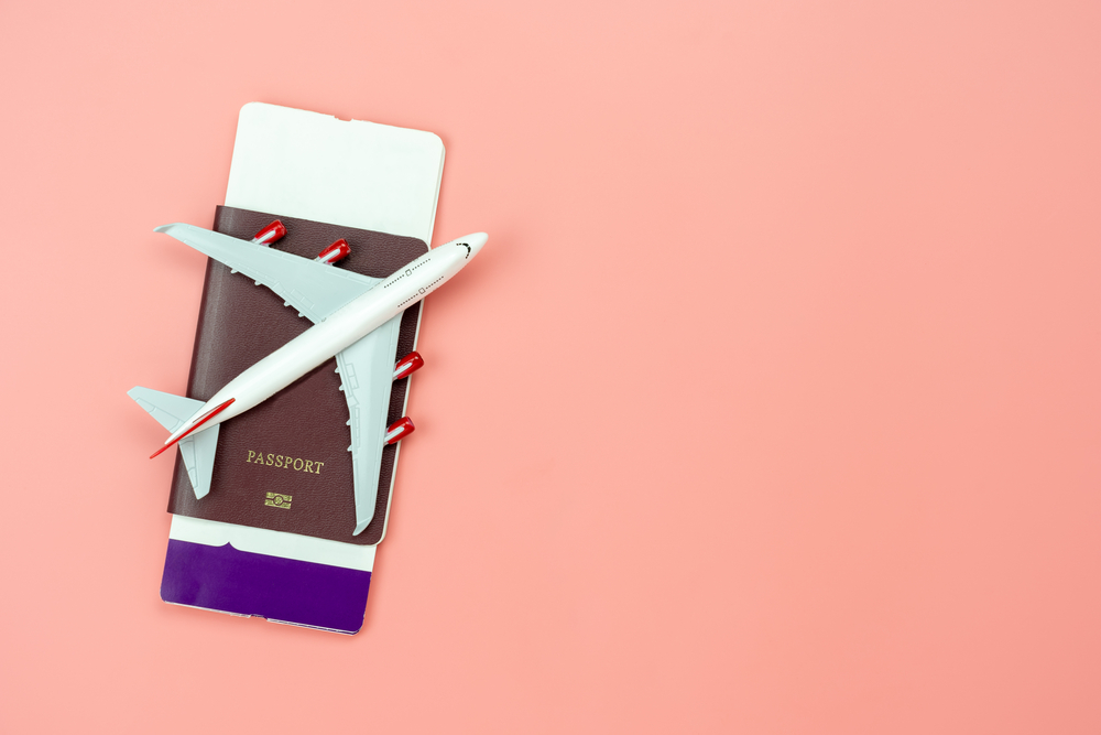 Minimalist Packing List for Females: Essential Items and Practical Tips. 
 Table top view accessory of accessory travel in holiday background concept.Flat lay of airplane with passport and boarding pass ticket on modern rustic pink paper at home studio office desk.copy space